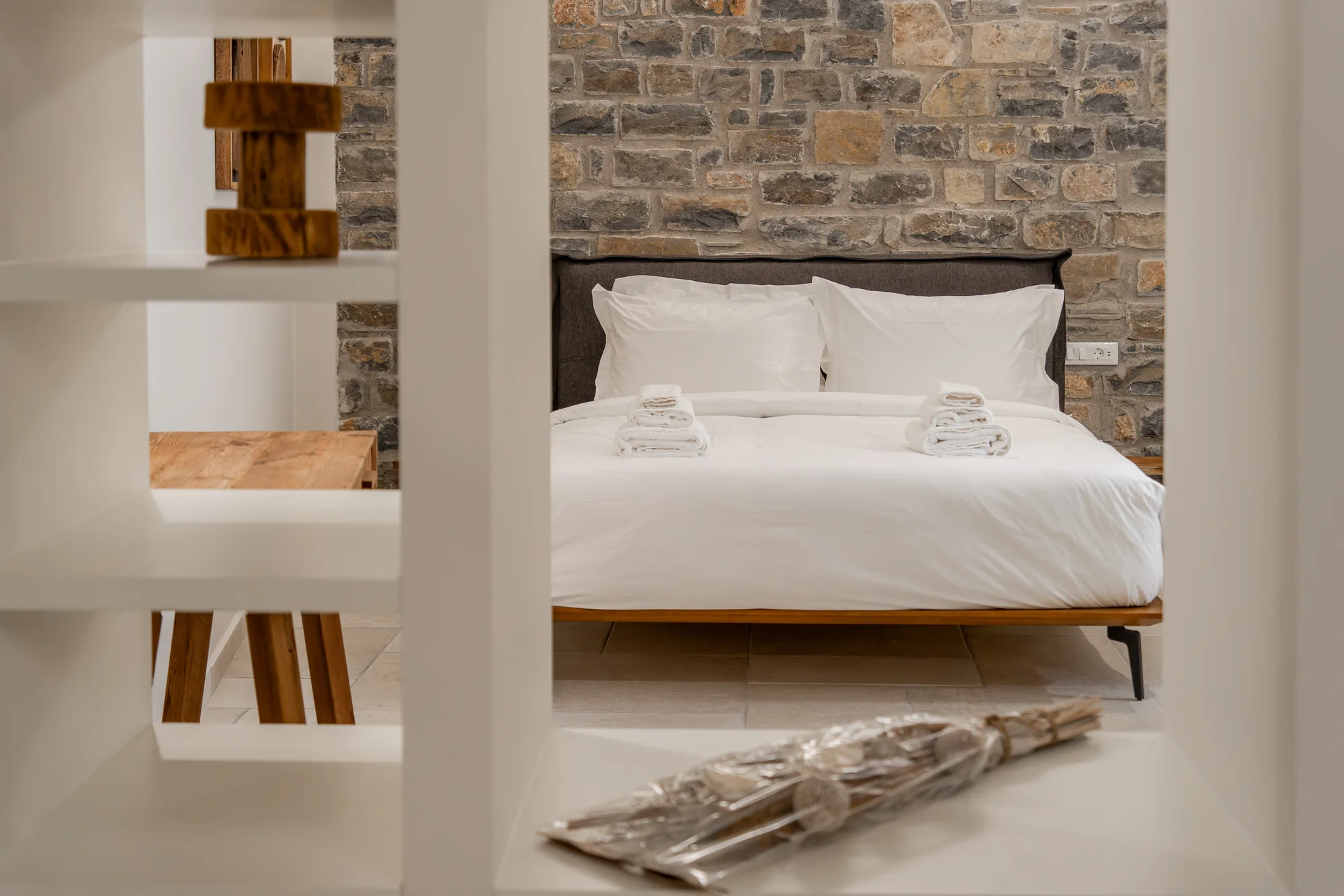 AEOS bedroom with custom shelving and a natural stone wall
