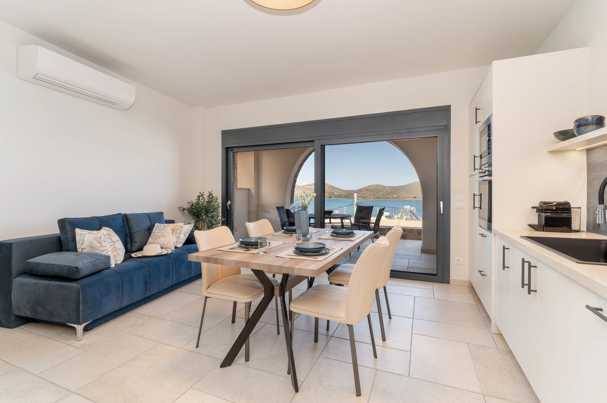 Bright AEOS living and dining space opening toward a sea-view terrace